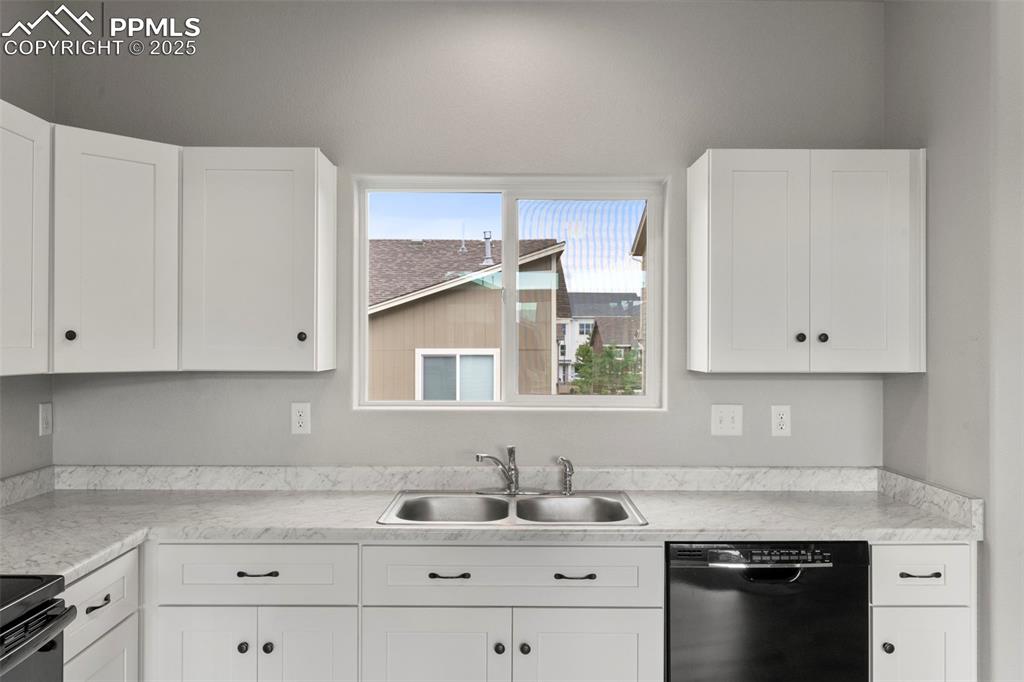 Image 11 of 22: Kitchen featuring black appliances, light countertops, and white cabinets