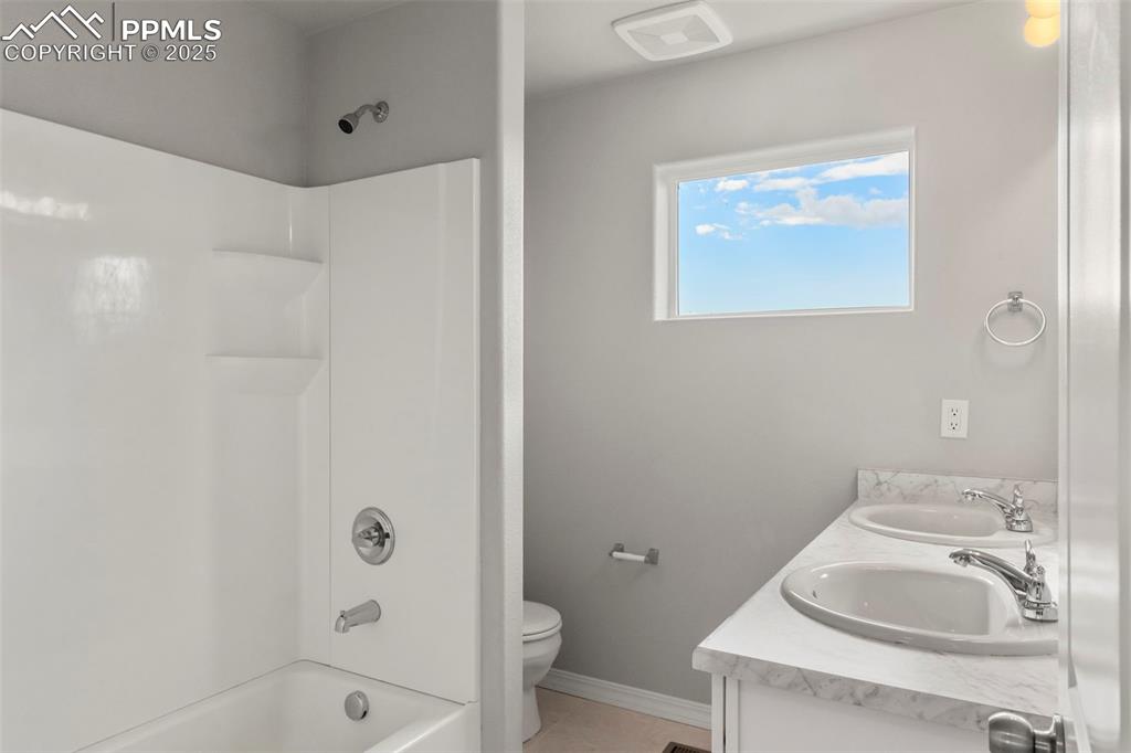 Image 14 of 22: Bathroom with shower / bath combination, double vanity, and light tile patt