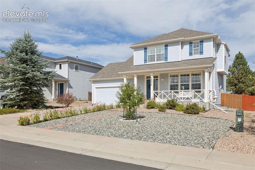 Image 34 of 43: Front of home with porch swing and lovely flowers lining the entrance to th