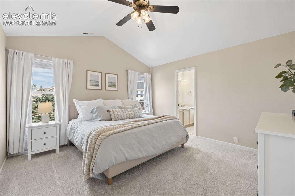 Image 5 of 43: Primary bedroom with vaulted ceilings, ceiling fan, and ensuite bathroom
