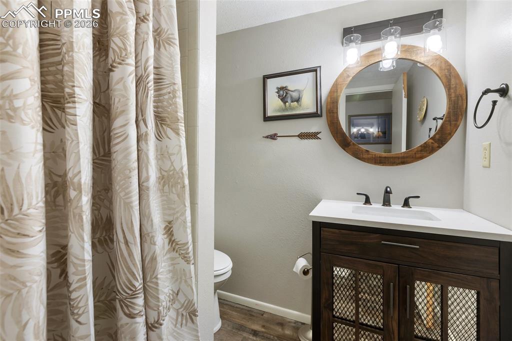 Image 19 of 36: Bathroom with curtained shower, vanity, and wood finished floors