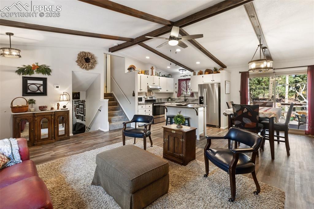 Image 33 of 36: Living area featuring wood finished floors, stairs, a chandelier, and ceili