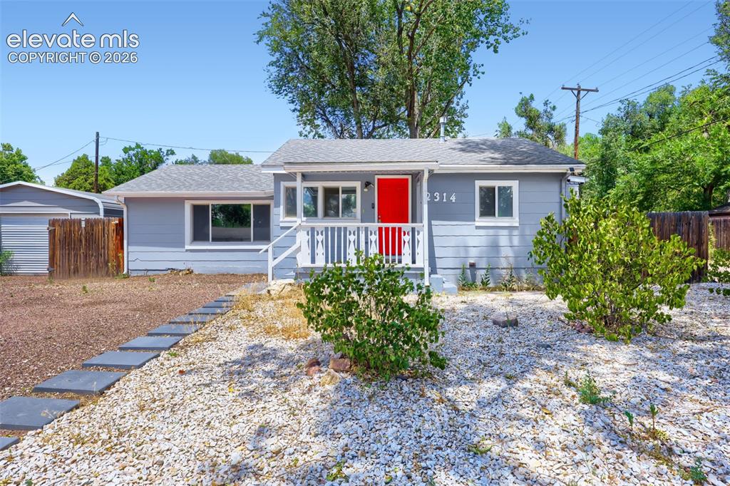 Caption: Single-story residence featuring light blue siding and a vibrant red entry door