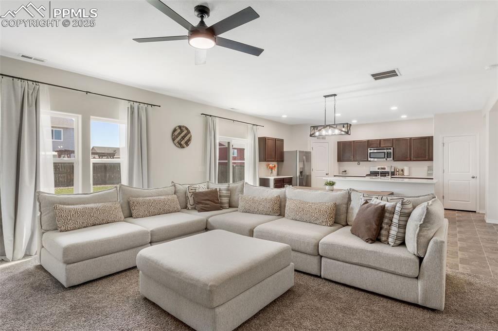 Image 6 of 25: Living area with light carpet, ceiling fan, and recessed lighting