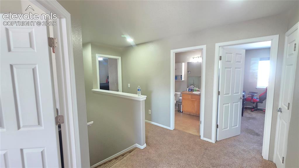 Image 18 of 35: Carpeted second-story landing with light beige wall paint