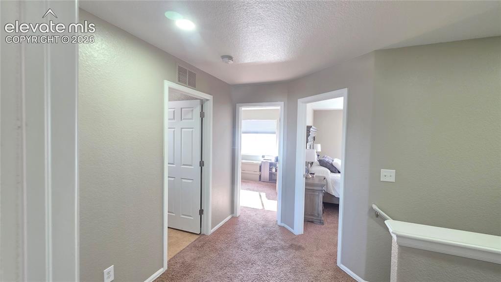 Image 19 of 35: Upper-level hallway featuring textured neutral paint, contrasting white tri