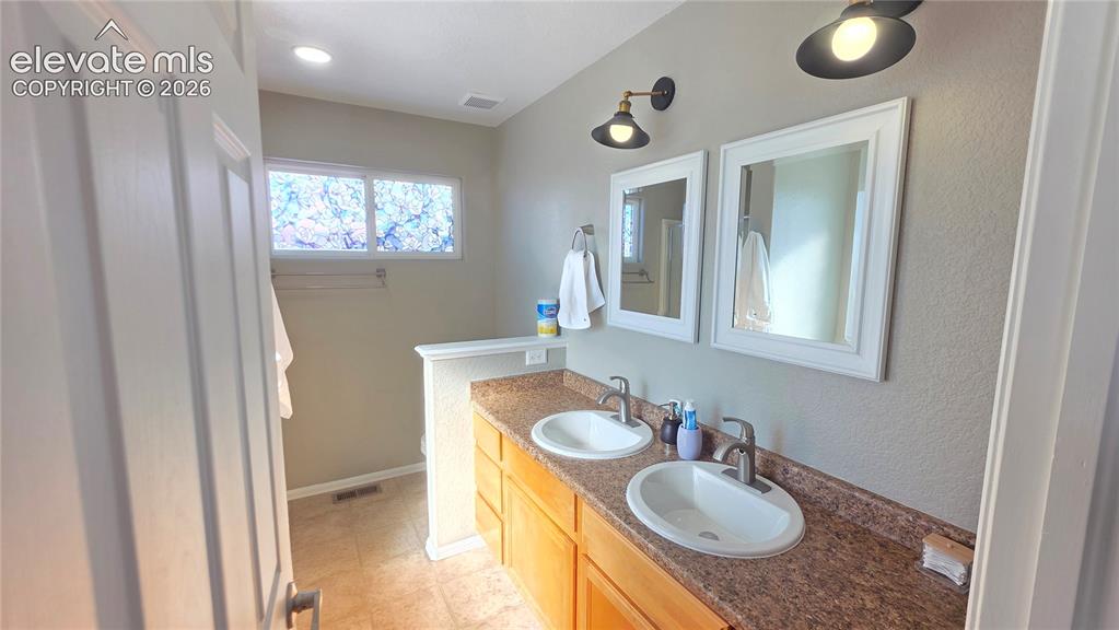Image 26 of 35: Dual vanity with integrated sinks and a speckled countertop