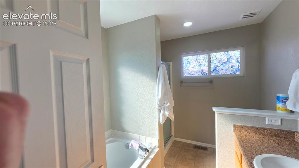 Image 27 of 35: Bathroom featuring a built-in tub, separate shower with glass enclosure, si