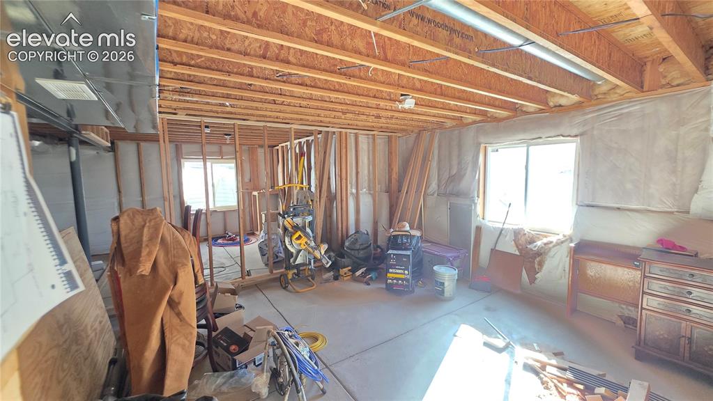 Image 32 of 35: Framed basement space with exposed wood joists, structural studs, and a con