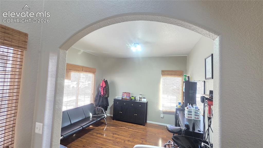 Image 5 of 35: Archway entrance framing a room with wood-finish flooring, light-toned wall