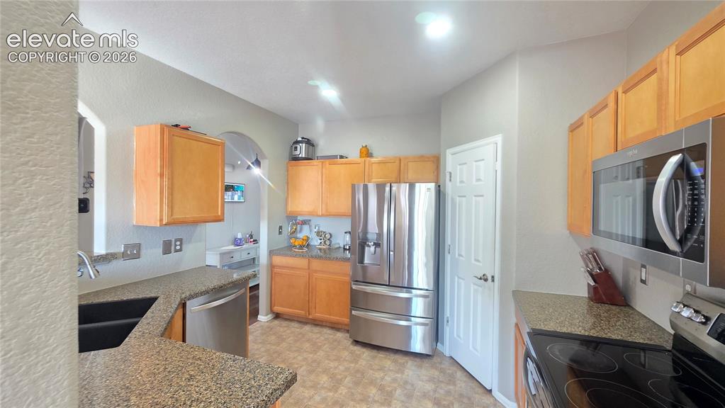 Image 9 of 35: Kitchen featuring light wood cabinetry, stainless steel appliances, speckle