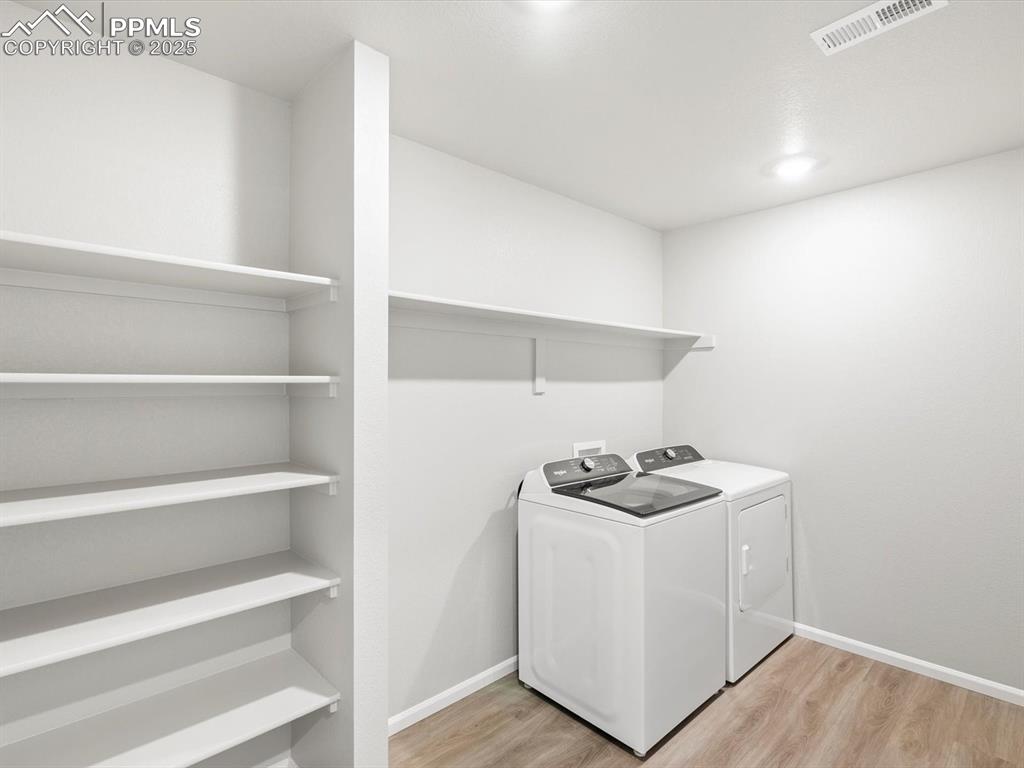 Image 13 of 25: Washroom with light wood-style flooring and washing machine and clothes dry