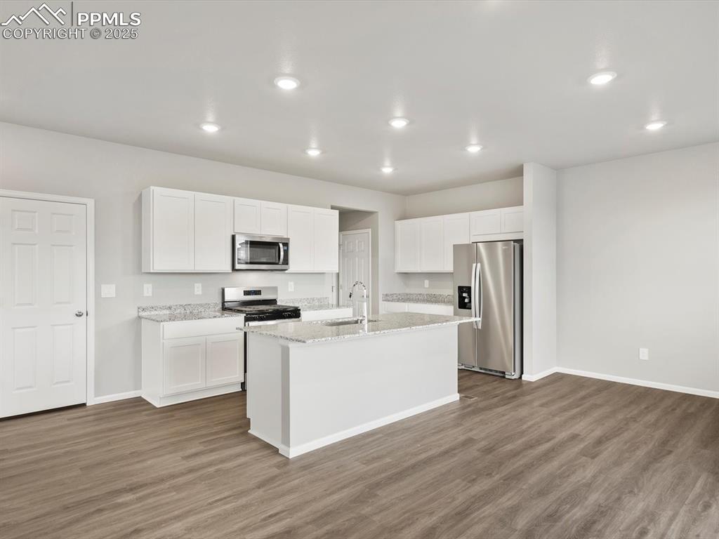 Image 3 of 25: Kitchen featuring stainless steel appliances, white cabinets, dark wood-sty