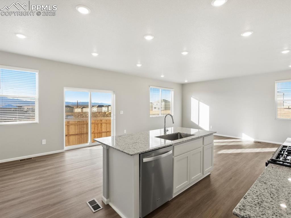 Image 5 of 25: Kitchen featuring light stone countertops, dark wood-type flooring, open fl