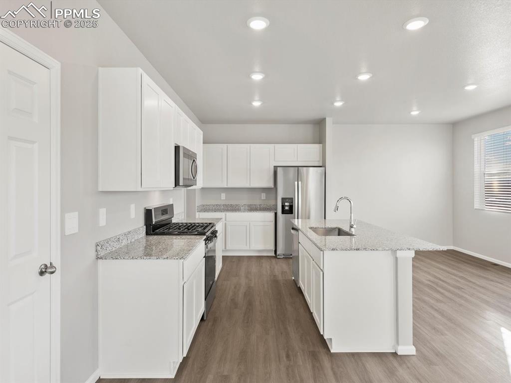 Image 8 of 25: Kitchen with appliances with stainless steel finishes, light stone counters
