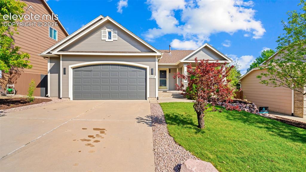 Image 1 of 46: Siding exterior with an arched garage door, concrete driveway, and mature l
