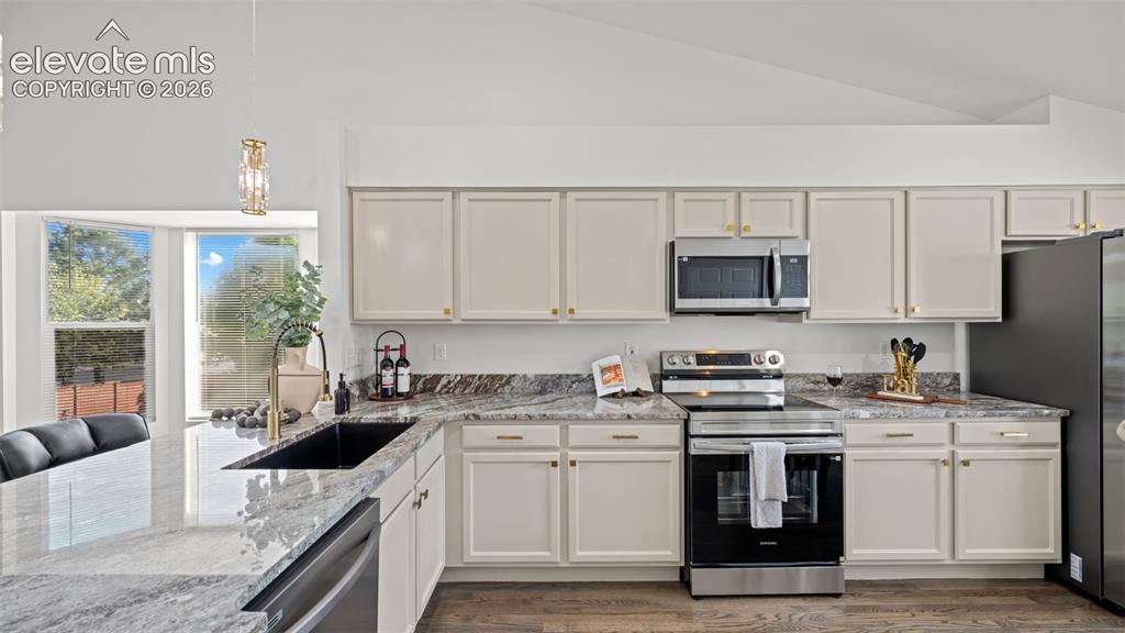 Image 10 of 46: Spacious kitchen featuring an expansive island, light-toned cabinetry, stai