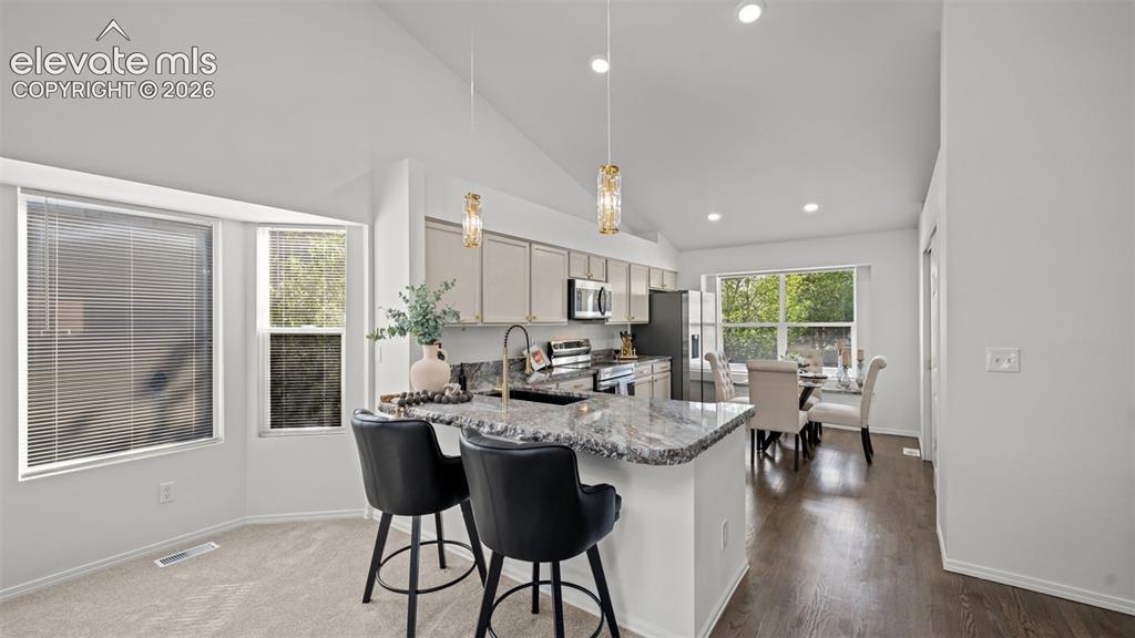 Image 11 of 46: Open-concept living area featuring a kitchen island with stone countertop,