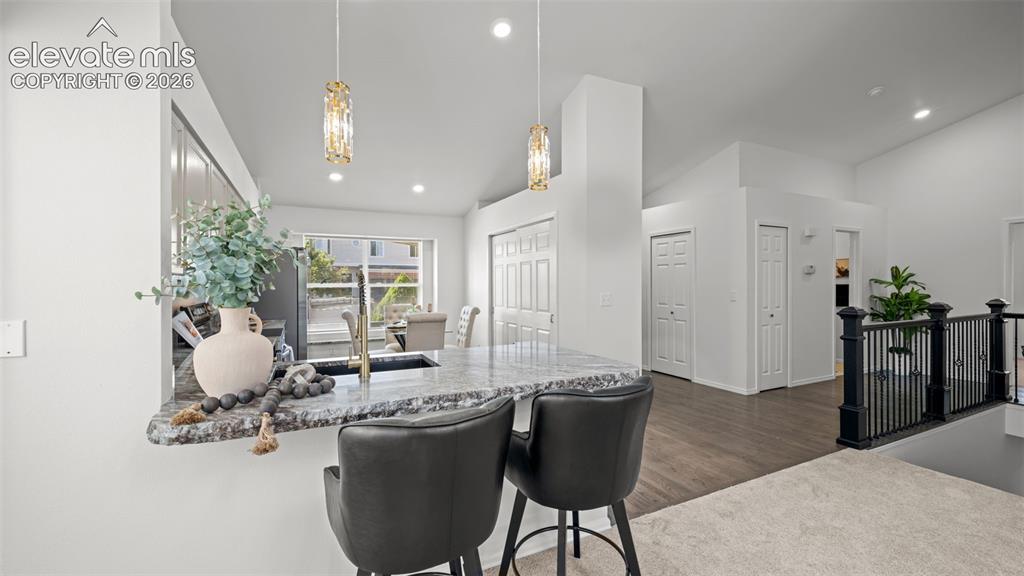 Image 12 of 46: Kitchen peninsula featuring a granite countertop, integrated sink with gold