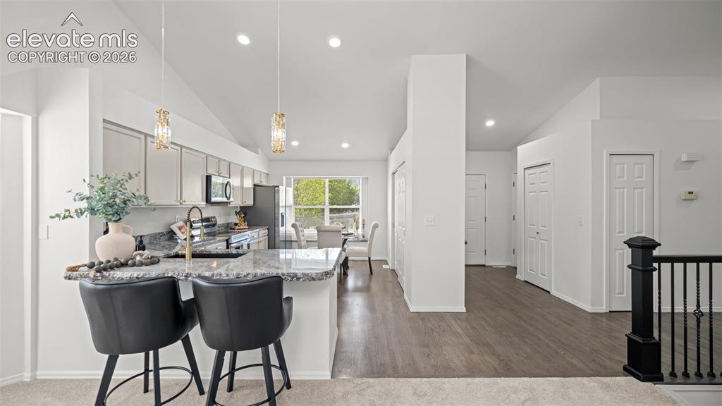 Image 13 of 46: Kitchen featuring light cabinetry, dark countertops, a breakfast bar, and s