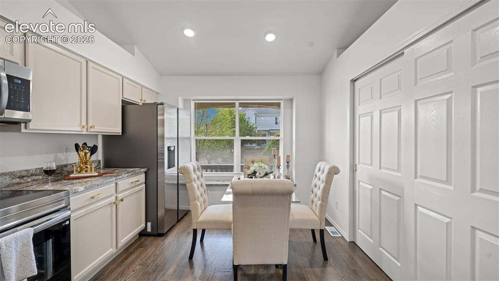 Image 15 of 46: Kitchen and dining area featuring light cabinetry, dark wood-finish floorin