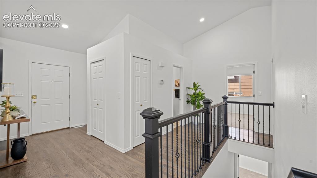 Image 16 of 46: Upper-level landing featuring vaulted ceilings, recessed lighting, wood-fin