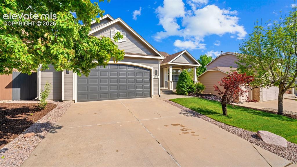 Image 2 of 46: Siding exterior with a covered porch entry, arched garage door, and mature