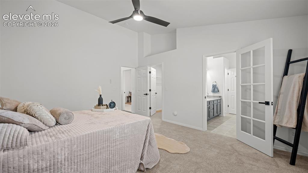 Image 21 of 46: Vaulted ceiling bedroom with a modern ceiling fan, plush carpet flooring, a