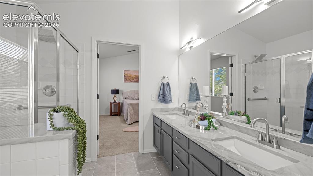 Image 23 of 46: Spacious bathroom featuring a double vanity with grey cabinetry, stone coun