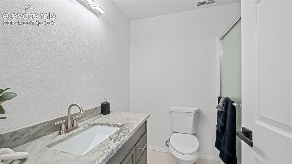 Image 29 of 46: Bathroom featuring a vanity with a light-toned stone countertop, undermount