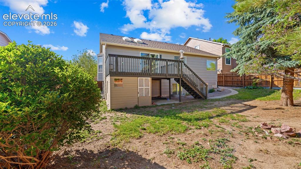 Image 33 of 46: Rear elevation featuring a raised deck with dark wood railing, exterior sid
