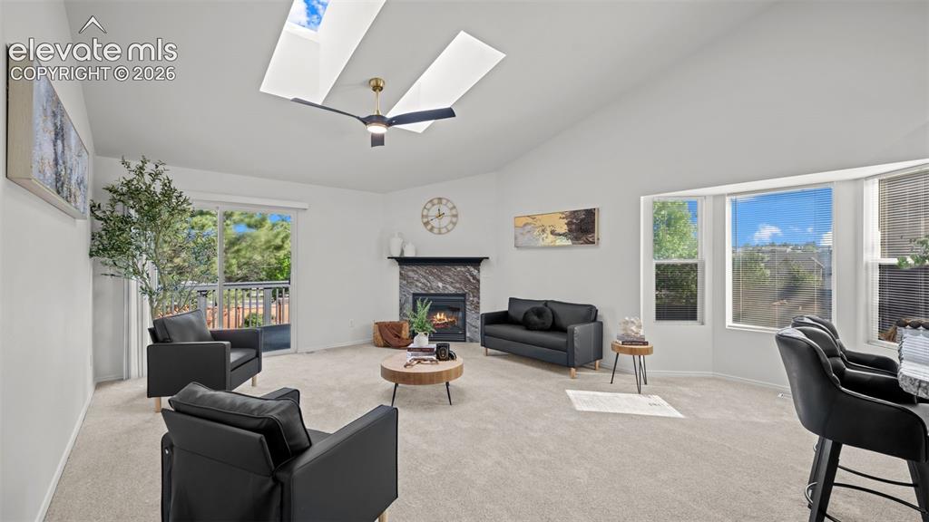 Image 6 of 46: Spacious living area featuring vaulted ceilings, dual skylights, a fireplac