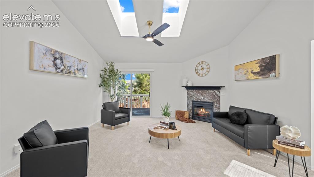 Image 8 of 46: Vaulted ceiling great room featuring two skylights, a ceiling fan, and a fi