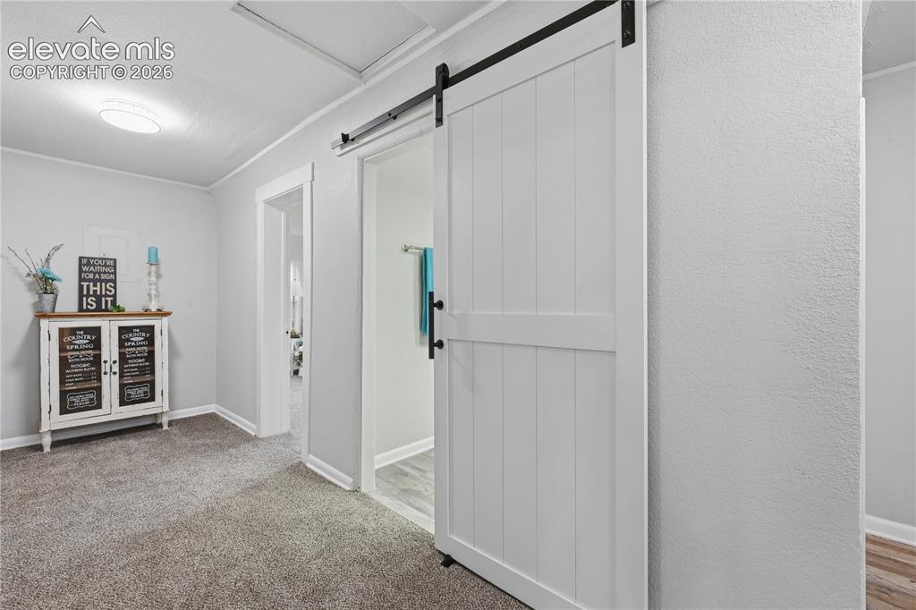 Image 18 of 50: The barn door entrance to the hall bathroom.