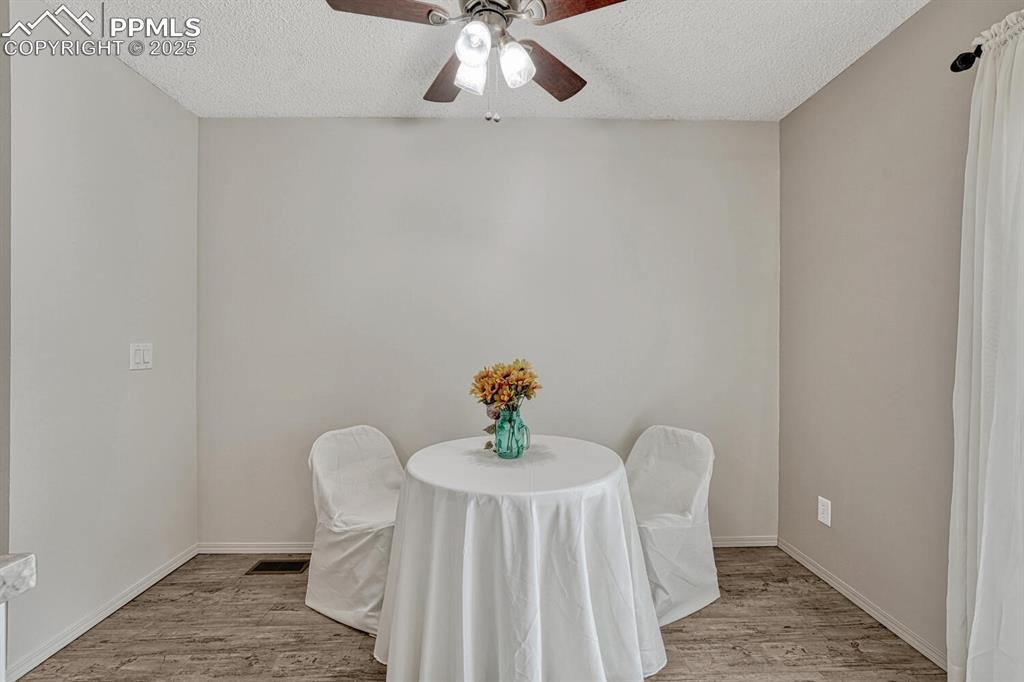 Image 14 of 50: Dining area with wood finished floors, a textured ceiling, a ceiling fan, a
