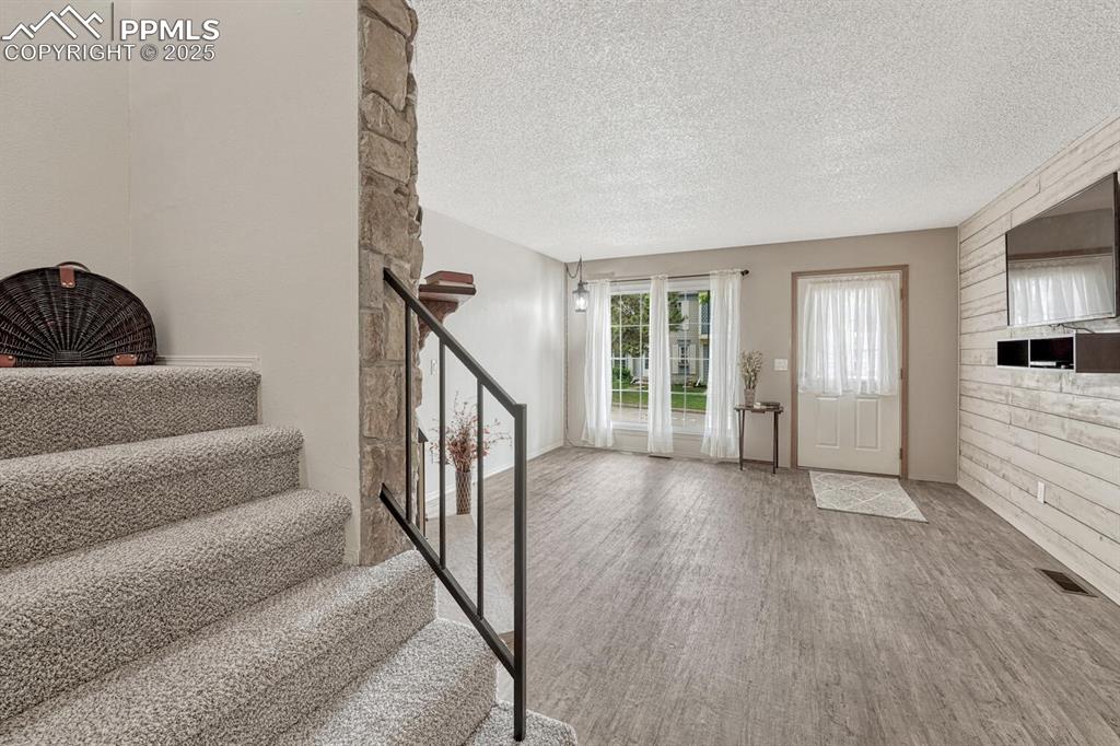Image 16 of 50: Foyer entrance with wood finished floors, stairs, and a textured ceiling