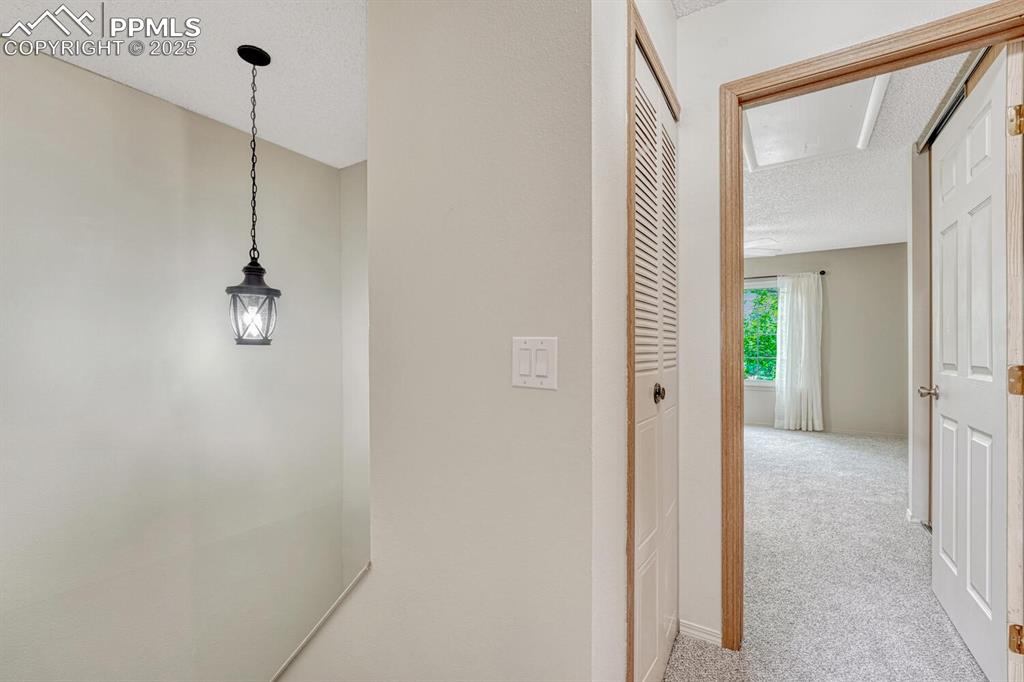 Image 17 of 50: Hall with carpet flooring, attic access, and a textured ceiling