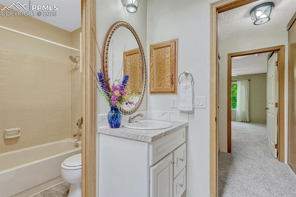 Image 23 of 50: Bathroom featuring vanity, toilet, shower / bath combination, and a texture