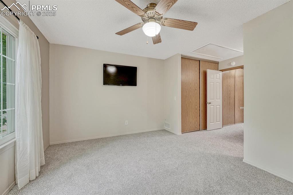 Image 25 of 50: Carpeted empty room with ceiling fan, plenty of natural light, baseboards,