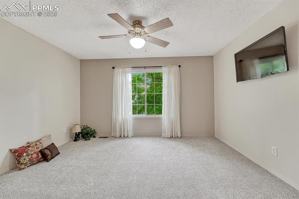 Image 27 of 50: Carpeted empty room with a textured ceiling, ceiling fan, and baseboards