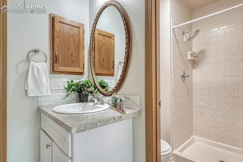 Image 29 of 50: Bathroom featuring tiled shower, vanity, and toilet