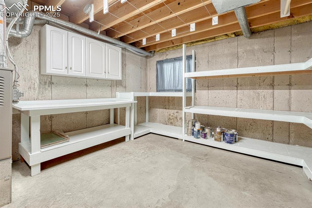 Image 31 of 50: Large unfinished basement room with window, built in shelving, and laundry