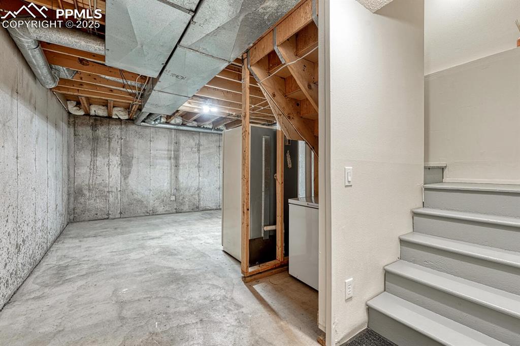Image 33 of 50: Unfinished below grade area with stairs and washer / clothes dryer