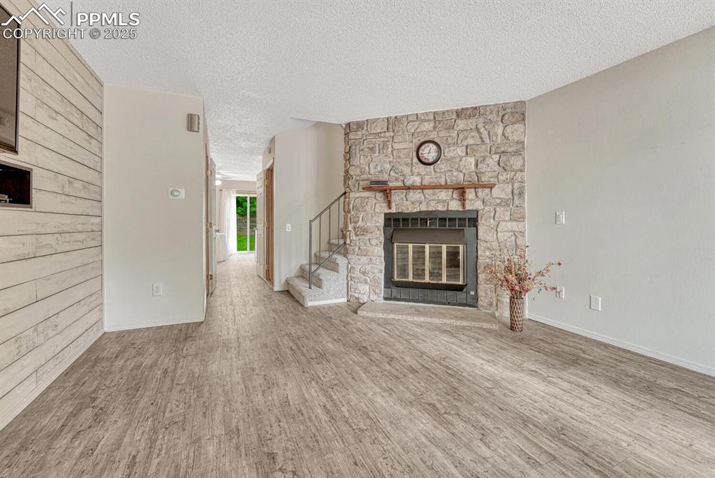 Image 5 of 50: Unfurnished living room featuring a textured ceiling, wood finished floors,