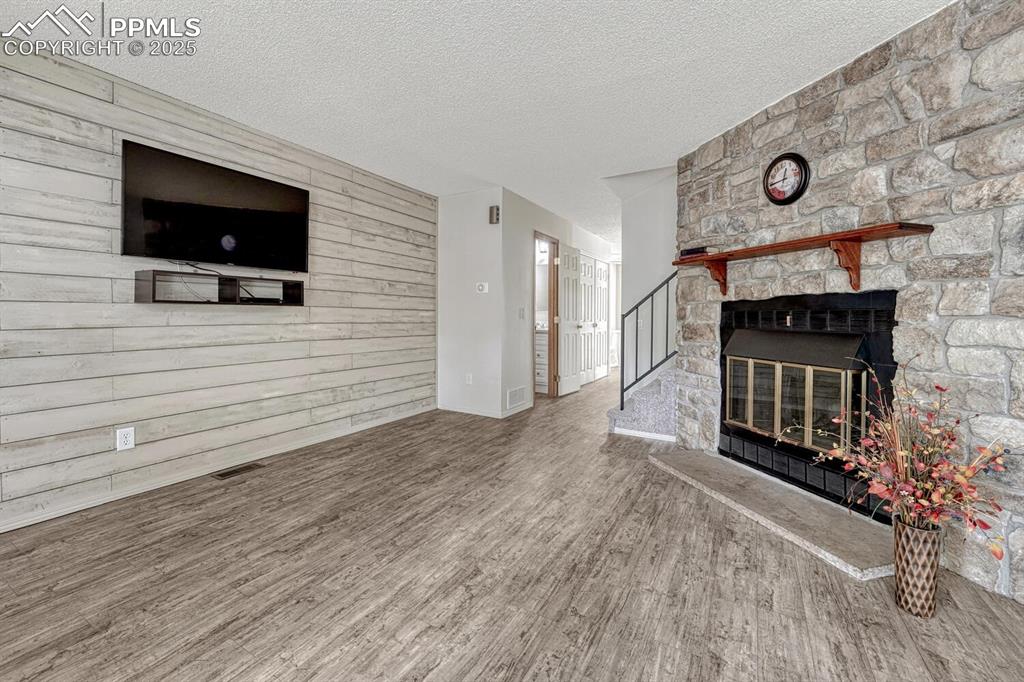 Image 6 of 50: Unfurnished living room with wood finished floors, a textured ceiling, a fi