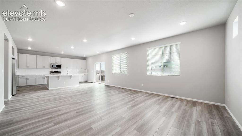 Image 10 of 34: Bright open-concept interior featuring light wood-finish flooring, recessed