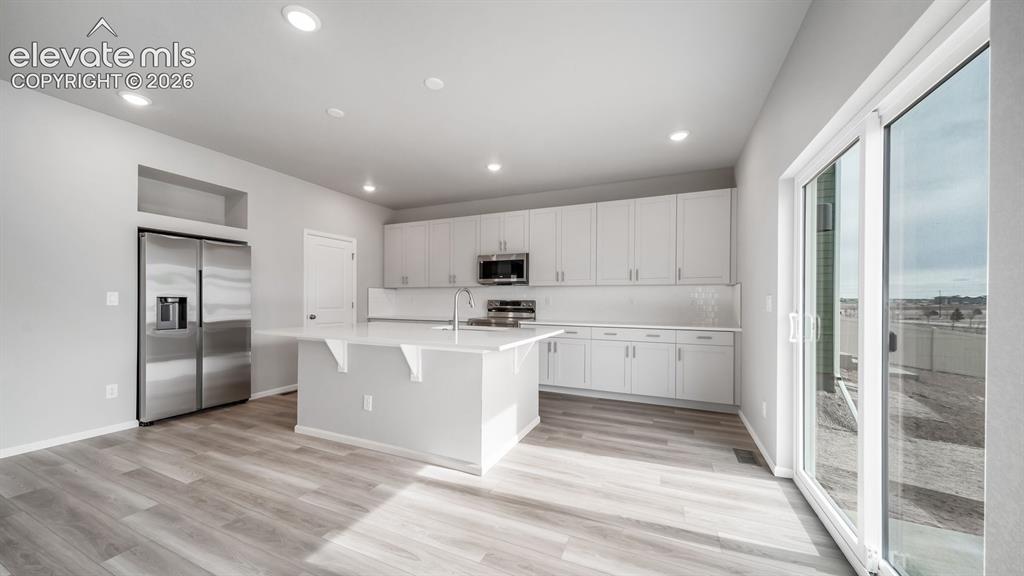 Image 13 of 34: Kitchen featuring white cabinetry, a central island with countertop seating