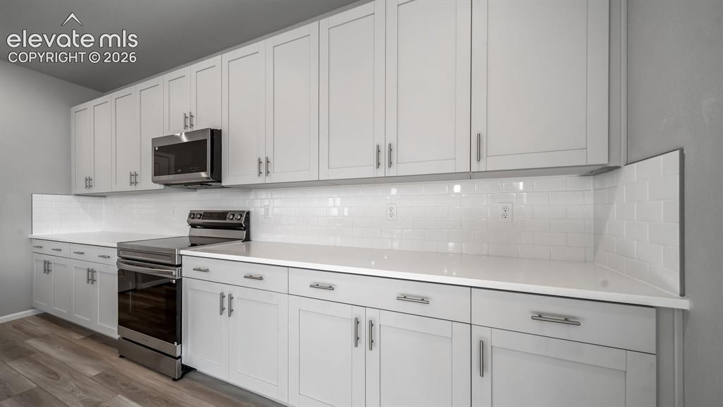 Image 14 of 34: Kitchen featuring white shaker-style cabinetry, white countertops, subway t