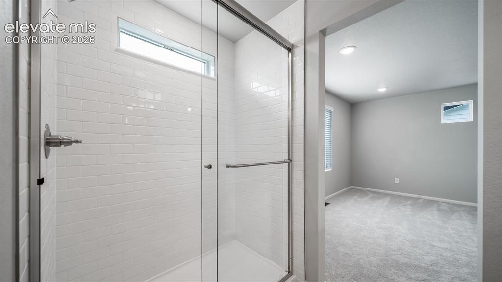 Image 23 of 34: Shower enclosure featuring subway tile surround, clear glass door, chrome h