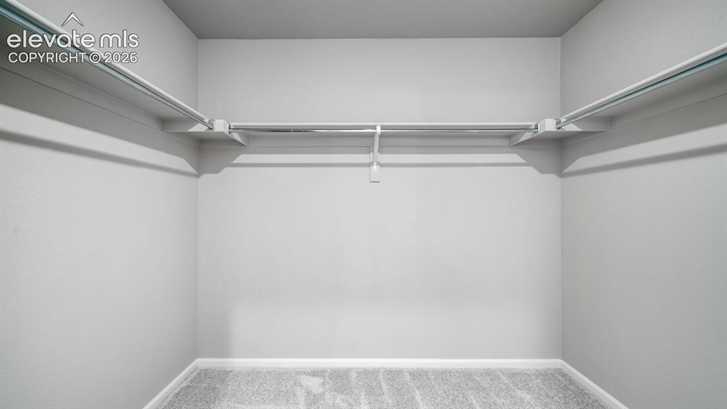 Image 25 of 34: Recessed closet featuring light gray walls, white trim, metal hanging rods,